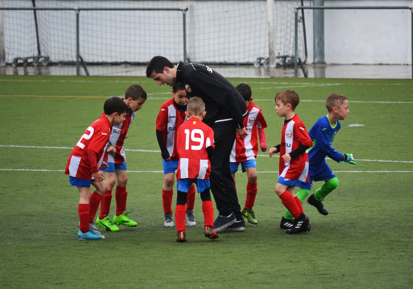 Entrenador acompañando a un grupo de niños futbolistas durante una práctica
